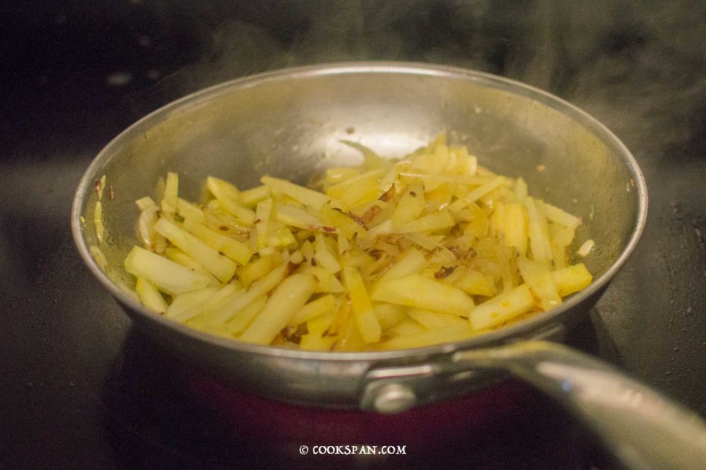 Potatoes, turmeric and salt being mixed