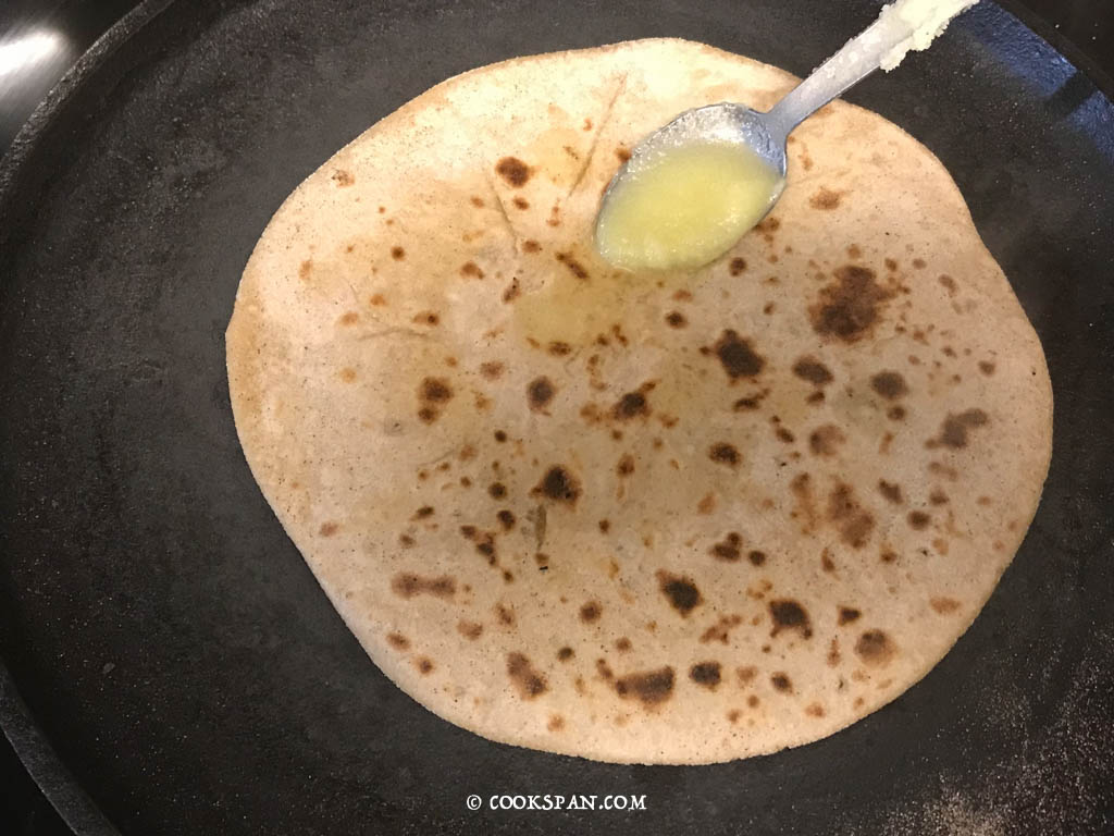 Adding Ghee to season the Poli