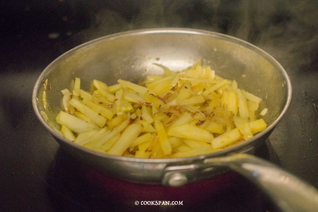 Potatoes, turmeric and salt being mixed